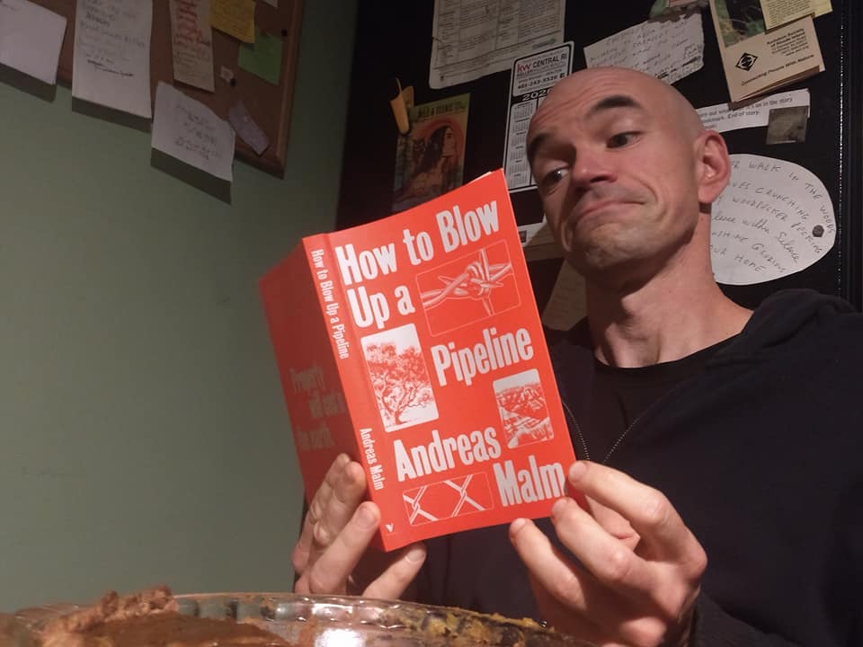 Tim reads "How To Blow Up a Pipeline" by Andreas Malm with a Mischievous Expression on his Face